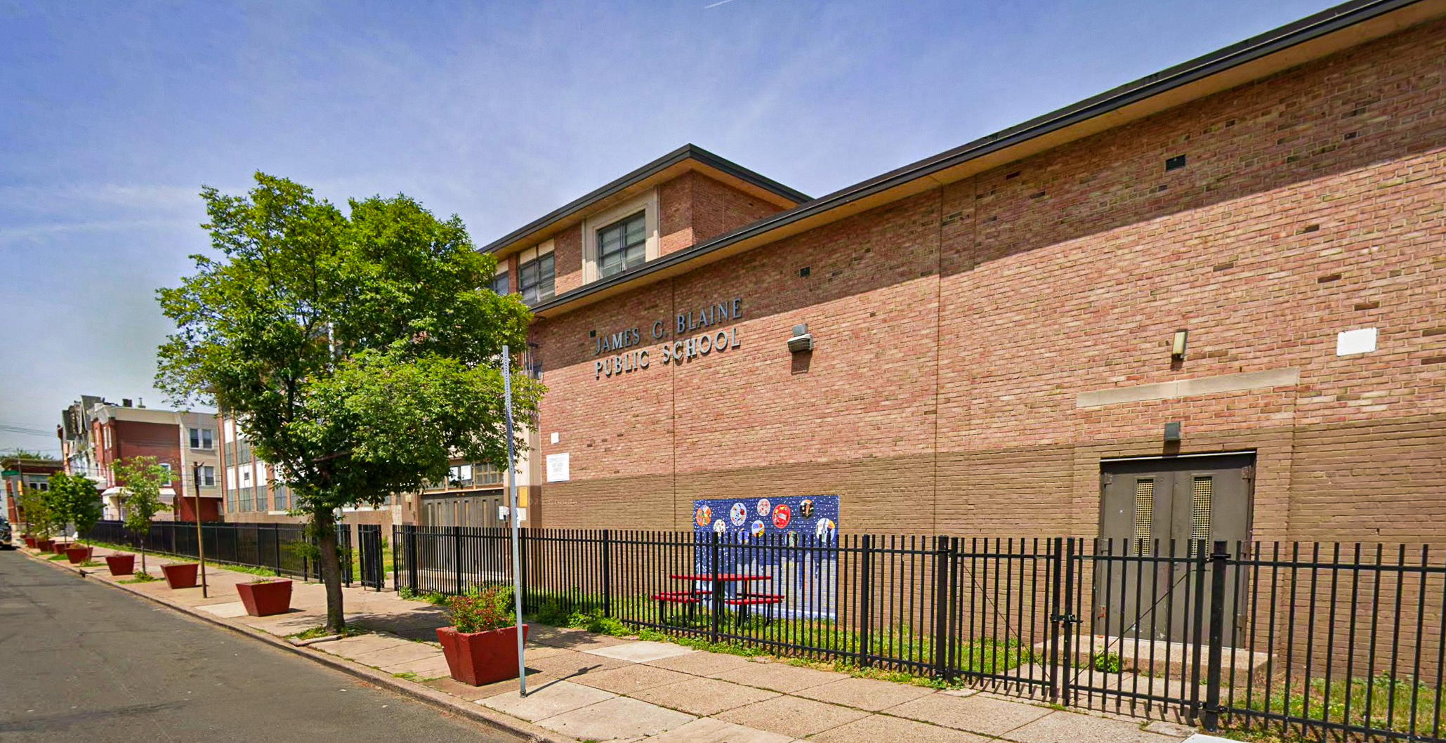 Exterior of James G. Blaine Public School in Philadelphia, showing the brick school building and fenced schoolyard.