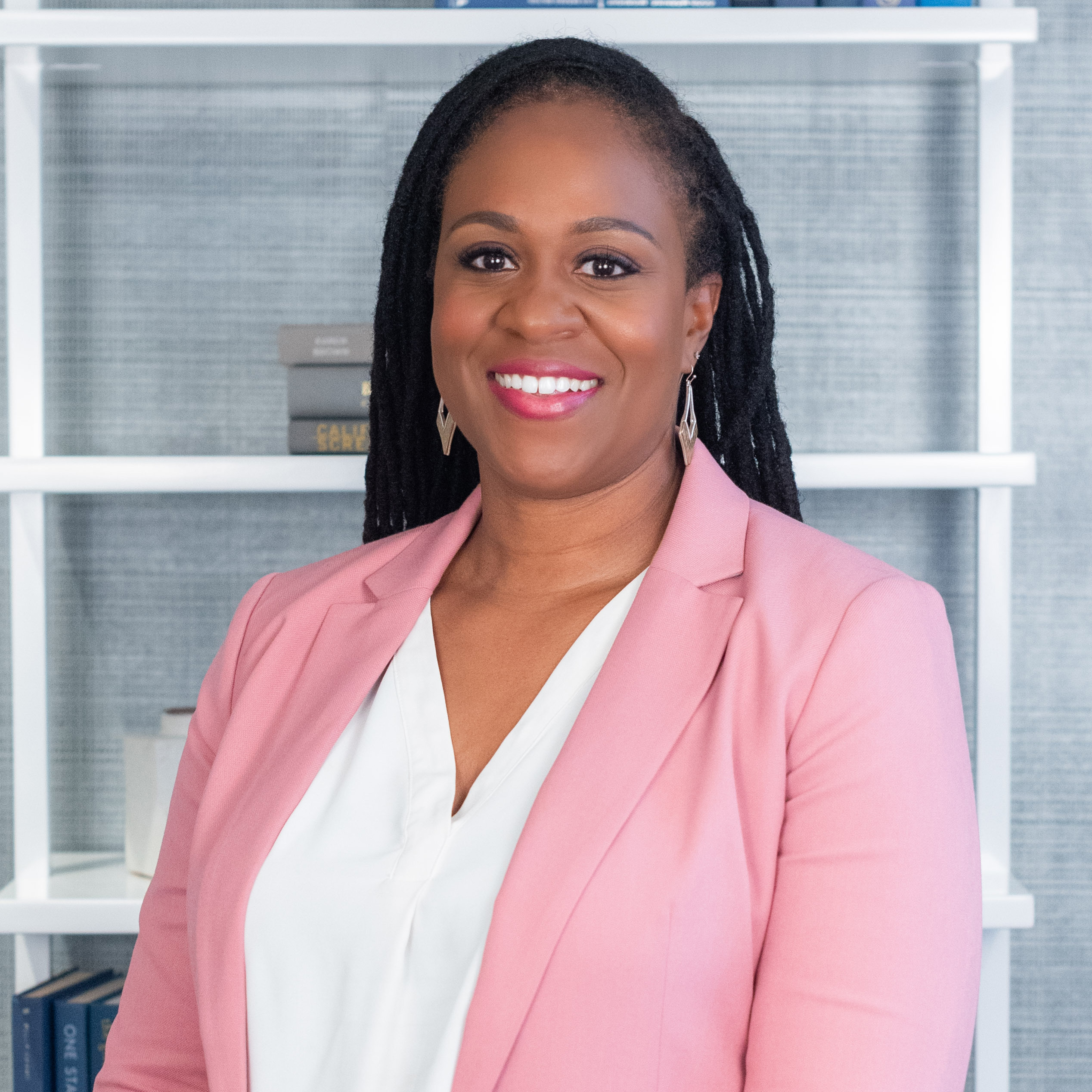 Principal Gianeen Anyika smiles for a professional portrait wearing a pink blazer.
